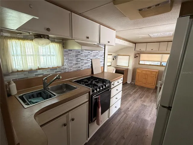 a kitchen that has a sink wooden floor and a stove top oven