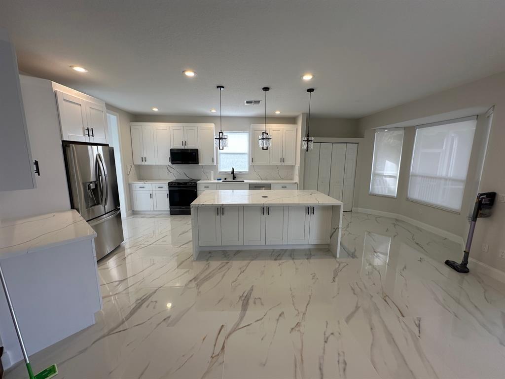 12763 Hyland Circle Boca Raton, FL 33428 - Photo 4 of 10 a living room with stainless steel appliances furniture a fireplace a flat screen tv and a kitchen view