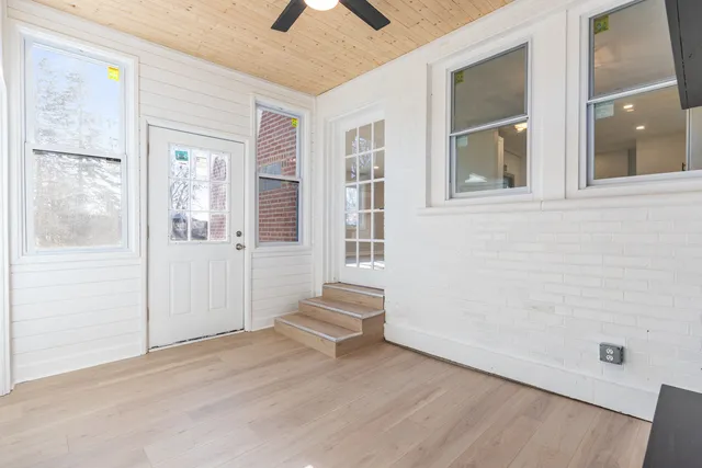 a view of an empty room with wooden floor and windows