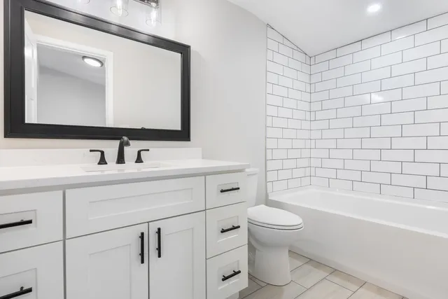 a bathroom with a bathtub shower sink mirror and toilet