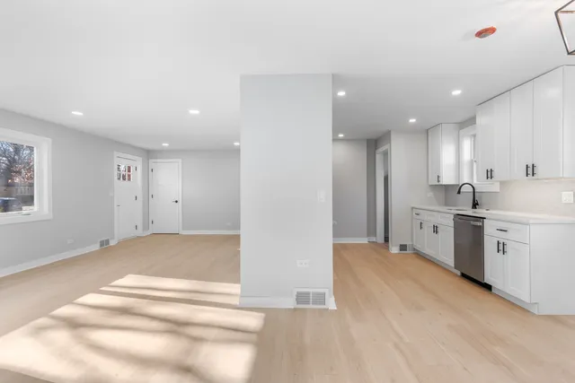 a view of a kitchen with white cabinets stainless steel appliances and a window