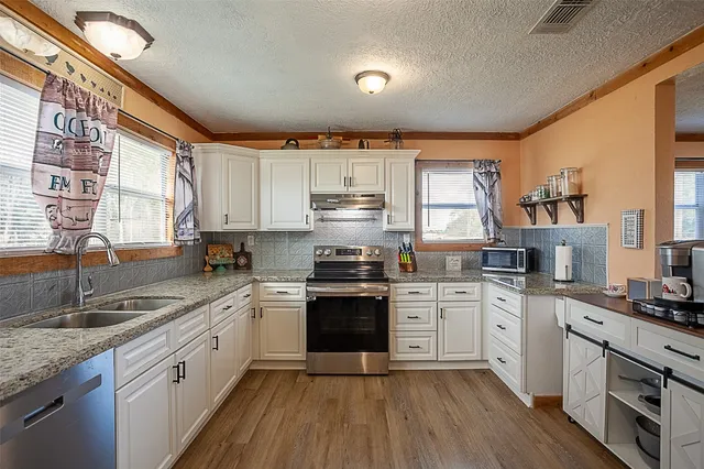 a kitchen with a sink cabinets wooden floor and stainless steel appliances
