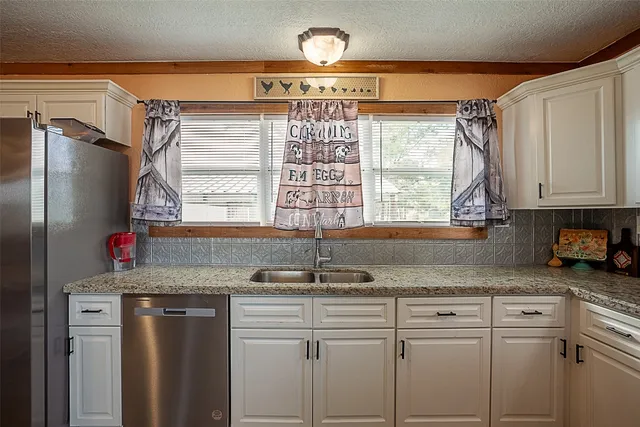 a kitchen with kitchen island granite countertop a sink window and cabinets