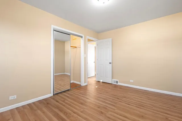 an empty room with wooden floor and closet