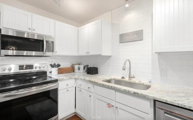 a kitchen with granite countertop a sink dishwasher stove and microwave with wooden cabinets