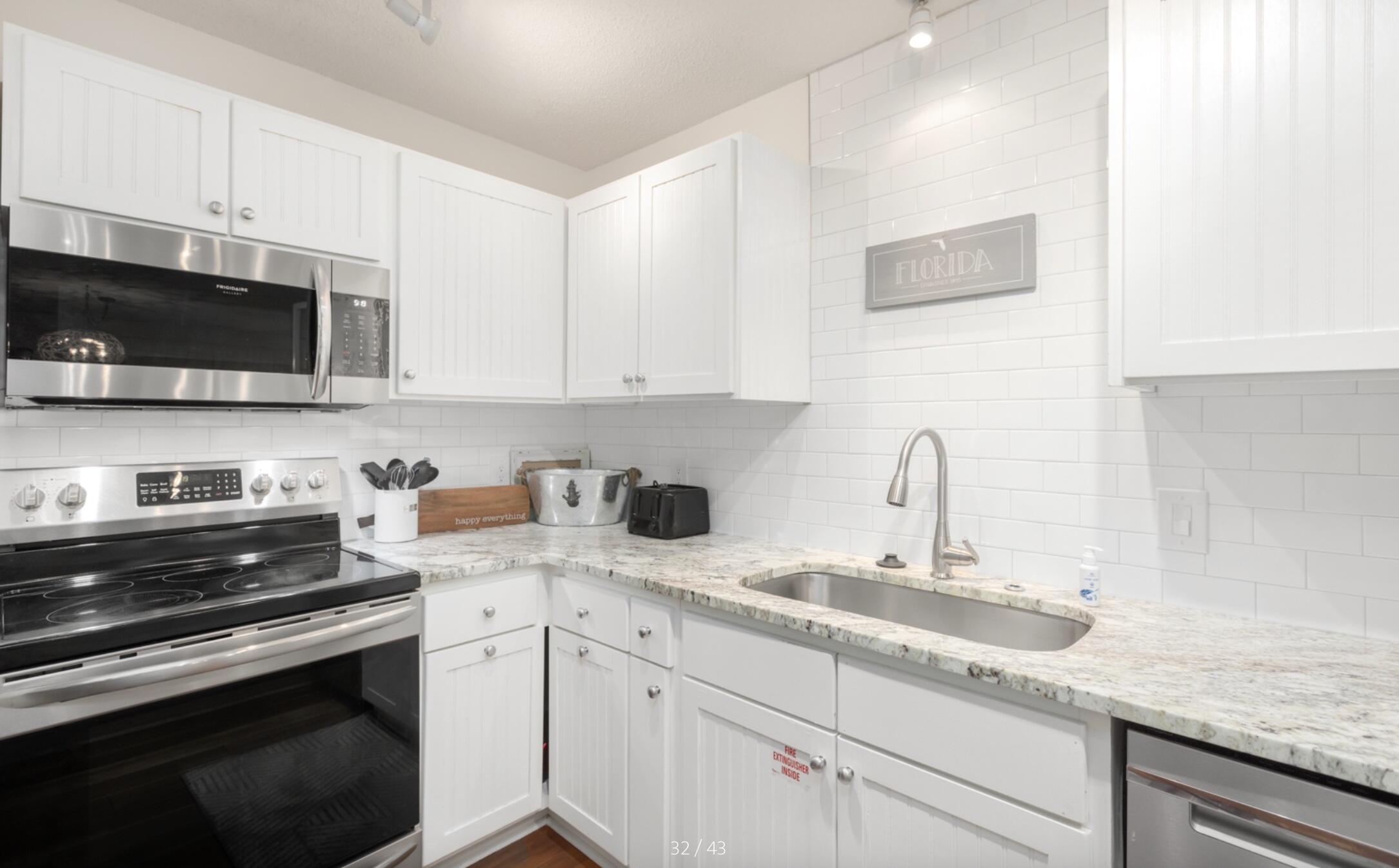 3799 East County Highway 30A, Unit E12 Santa Rosa Beach, FL 32459 - Photo 11 of 34 a kitchen with granite countertop a sink dishwasher stove and microwave with wooden cabinets
