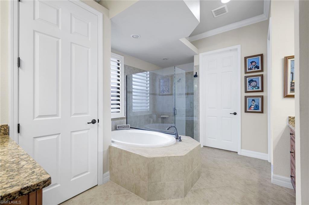 11050 Longwing Drive Fort Myers, FL 33912 - Photo 16 of 43 Bathroom with vanity, a garden tub, ornamental molding, a stall shower, and light tile patterned flooring