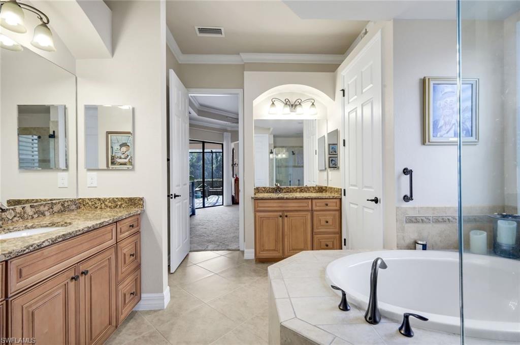 11050 Longwing Drive Fort Myers, FL 33912 - Photo 17 of 43 Bathroom with two vanities, crown molding, a garden tub, light tile patterned floors, and a shower stall