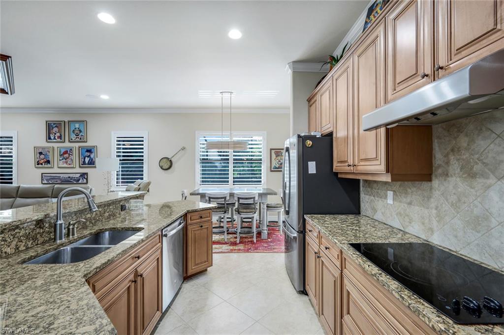 11050 Longwing Drive Fort Myers, FL 33912 - Photo 7 of 43 Kitchen with stainless steel appliances, light stone countertops, crown molding, under cabinet range hood, and pendant lighting