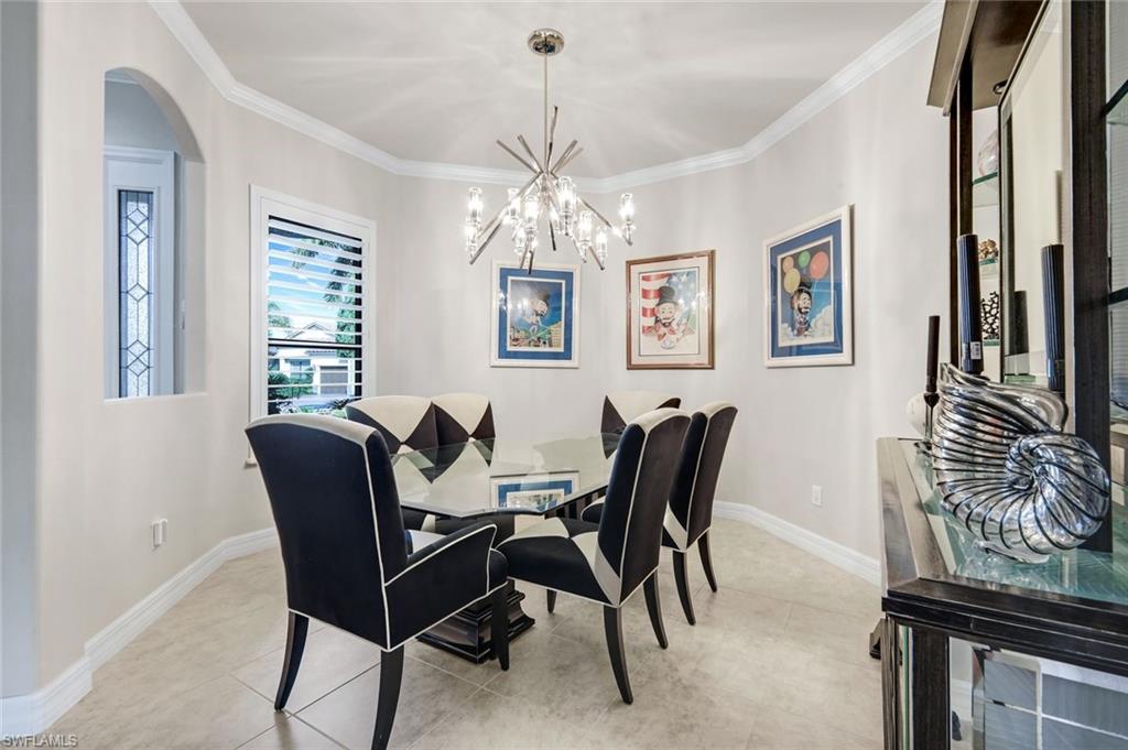 11050 Longwing Drive Fort Myers, FL 33912 - Photo 10 of 43 Dining room featuring arched walkways, a chandelier, crown molding, and light tile patterned floors