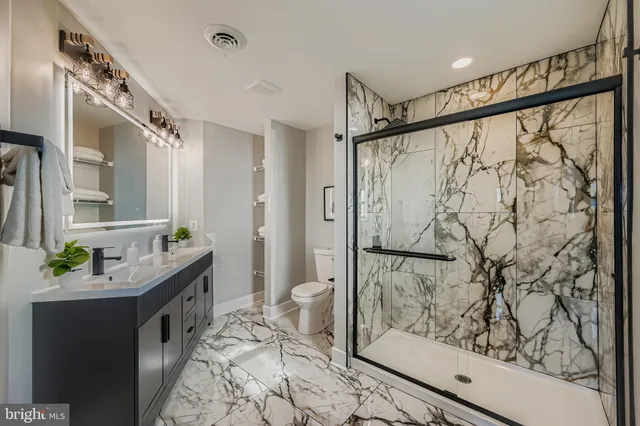a bathroom with a granite countertop sink a toilet and shower