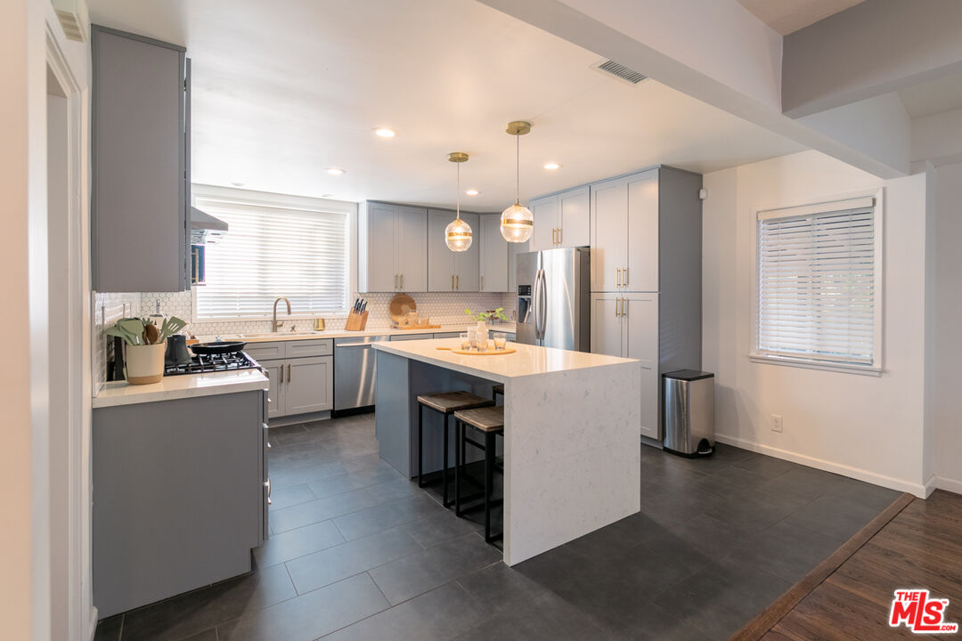 2415 8th Avenue Los Angeles, CA 90018 - Photo 13 of 55 a kitchen with kitchen island a sink stainless steel appliances cabinets and a window