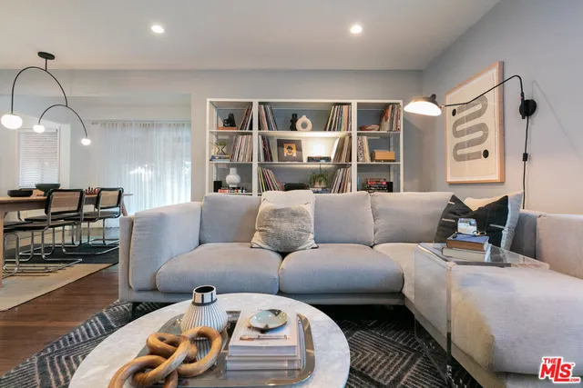 a living room with furniture a wooden floor and next to a window
