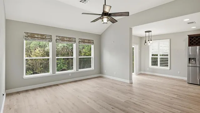 a view of an empty room with a window and wooden floor