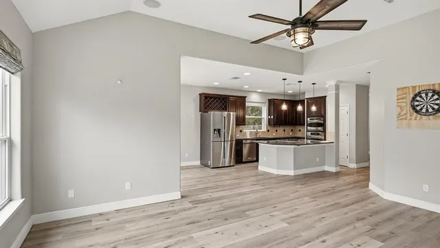 a large kitchen with stainless steel appliances kitchen island a large counter top and wooden floor
