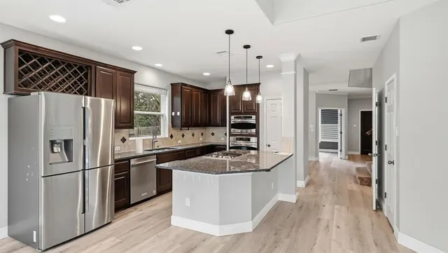 a kitchen with stainless steel appliances granite countertop a refrigerator a sink and a stove