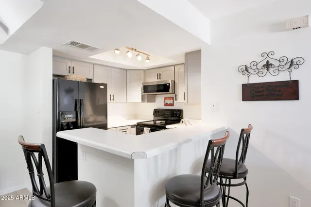 a kitchen with stainless steel appliances a dining table chairs and a refrigerator