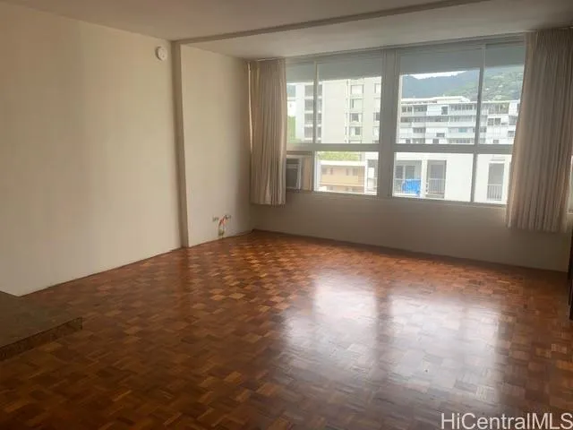 a view of an empty room with wooden floor and a window