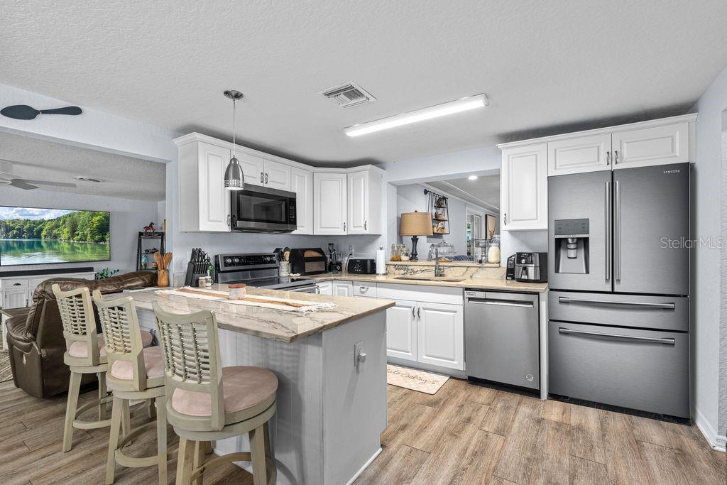 925 Flagler Avenue Edgewater, FL 32132 - Photo 5 of 35 a kitchen with stainless steel appliances granite countertop a refrigerator a stove top oven a sink dishwasher and white cabinets with wooden floor