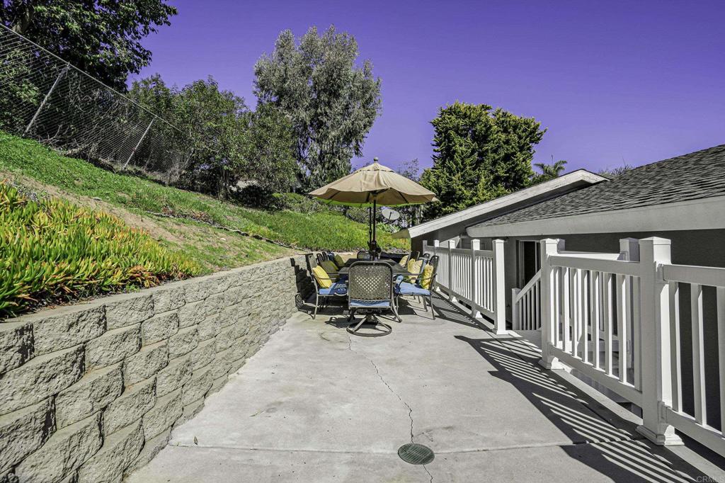 1460 Orpheus Avenue Encinitas, CA 92024 - Photo 22 of 24 a view of a patio with a table and chairs under an umbrella with a garden