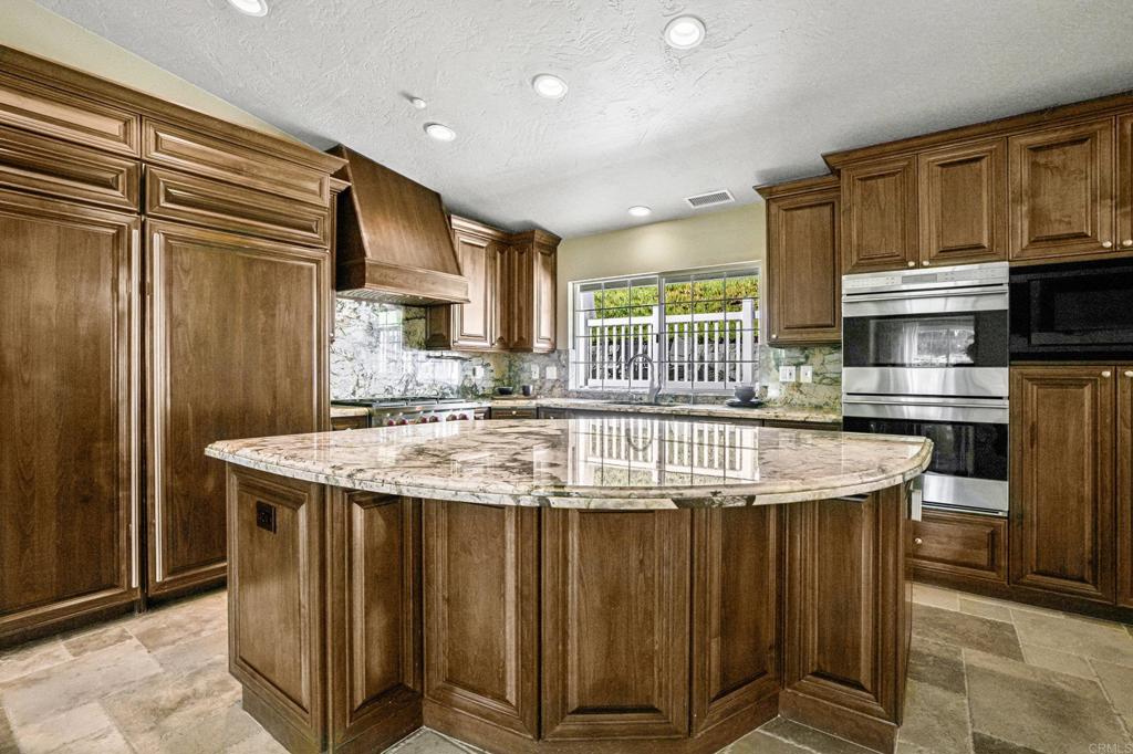 1460 Orpheus Avenue Encinitas, CA 92024 - Photo 5 of 24 a kitchen with kitchen island granite countertop a stove and a wooden cabinets