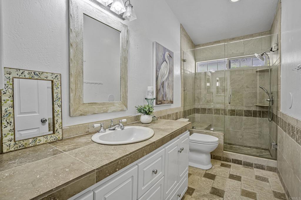 1460 Orpheus Avenue Encinitas, CA 92024 - Photo 10 of 24 a bathroom with a granite countertop sink a toilet a mirror and shower