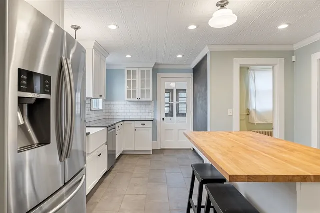 a kitchen with stainless steel appliances granite countertop a refrigerator a sink dishwasher a stove and white countertops with wooden floor