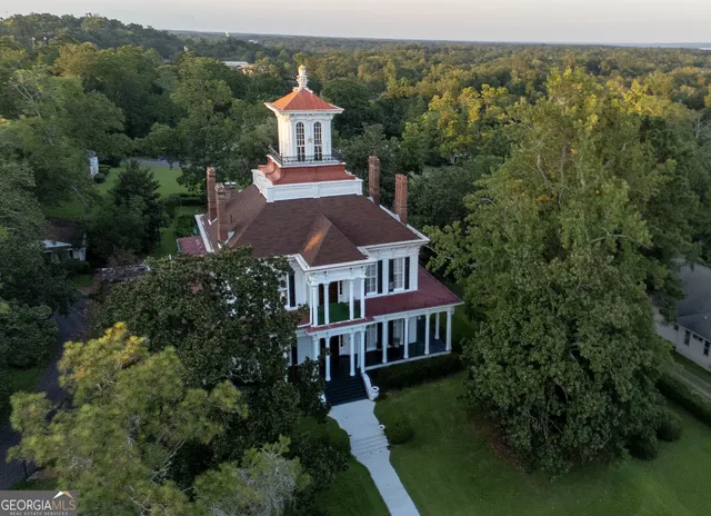 an aerial view of a house with balcony and trees al around