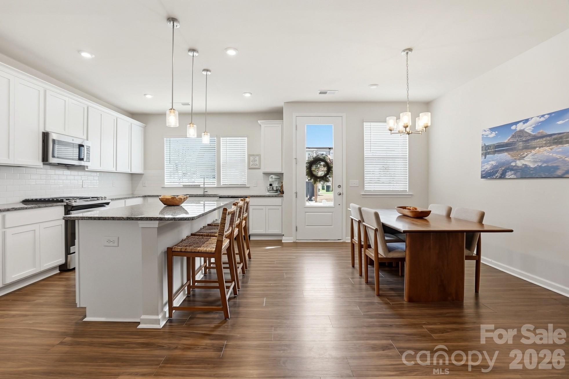 6351 Lopez Court Kannapolis, NC 28081 - Photo 8 of 48 a kitchen with stainless steel appliances granite countertop a stove a refrigerator a kitchen island a dining table and chairs with wooden floor