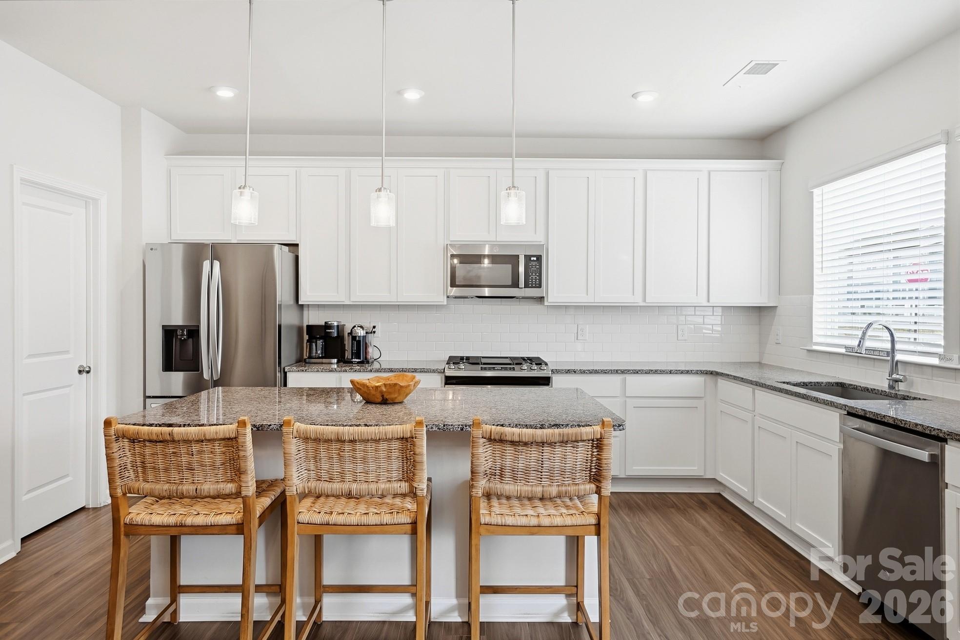 6351 Lopez Court Kannapolis, NC 28081 - Photo 10 of 48 a kitchen with stainless steel appliances granite countertop a stove a sink a microwave a refrigerator and white cabinets with wooden floors