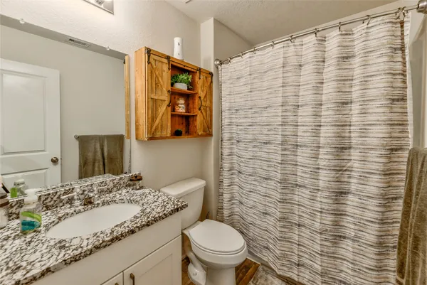 a bathroom with a granite countertop toilet and a sink