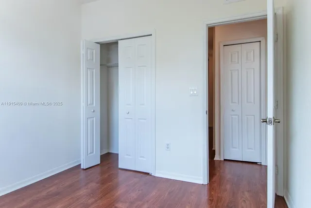 an empty room with wooden floor & closet area