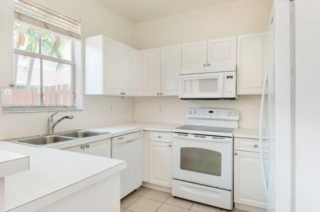 a kitchen with white cabinets and white appliances