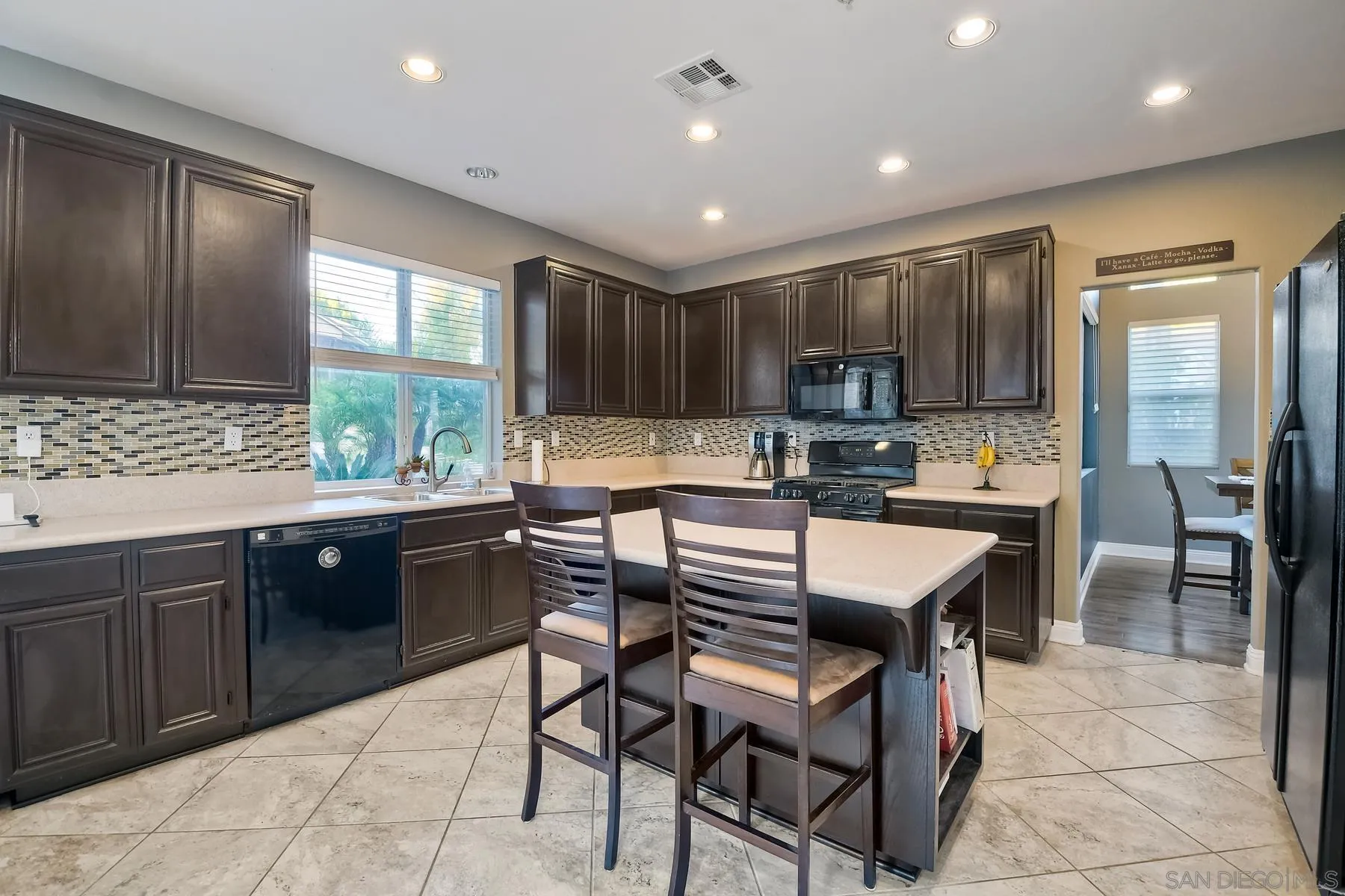 10340 Hitching Post Way Santee, CA 92071 - Photo 14 of 50 a kitchen with stainless steel appliances granite countertop wooden cabinets a refrigerator a sink a stove a dining table and chairs