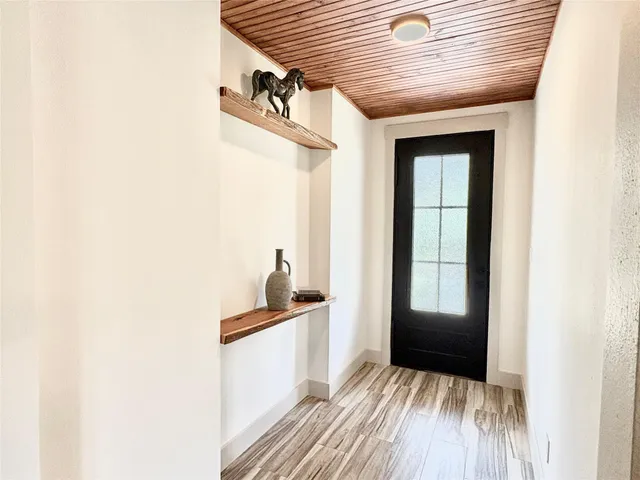 a view of a hallway with wooden floor and a bathroom