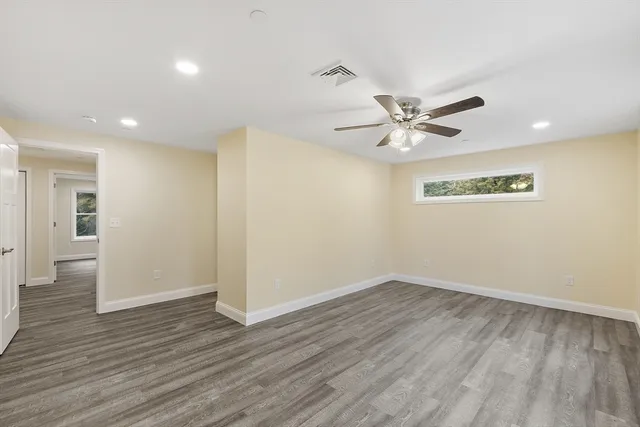 an empty room with wooden floor and ceiling fan