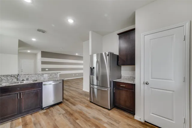 a kitchen with stainless steel appliances granite countertop wooden cabinets a sink stove and refrigerator