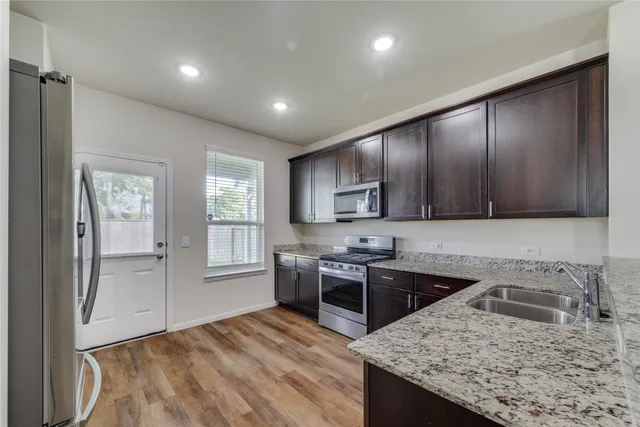a kitchen with stainless steel appliances granite countertop wooden cabinets granite counter tops and a stove