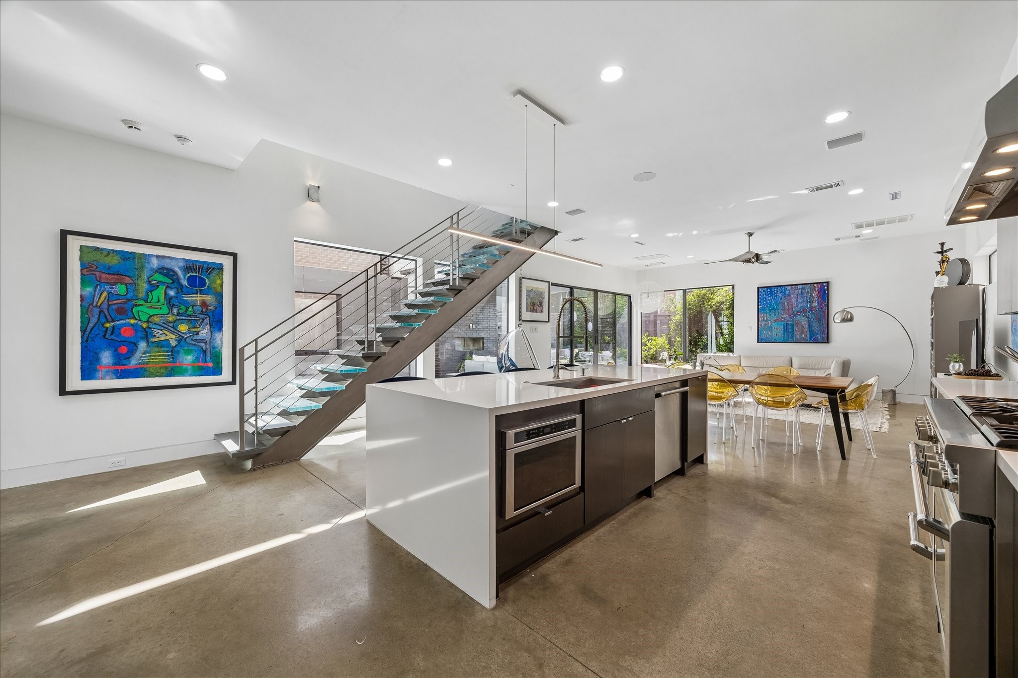 2014 Park Street Houston, TX 77019 - Photo 8 of 40 Experience seamless indoor-outdoor living with this open-concept space featuring a gourmet kitchen with a waterfall quartz island, sleek concrete flooring, and an LED backlit steel and glass staircase.