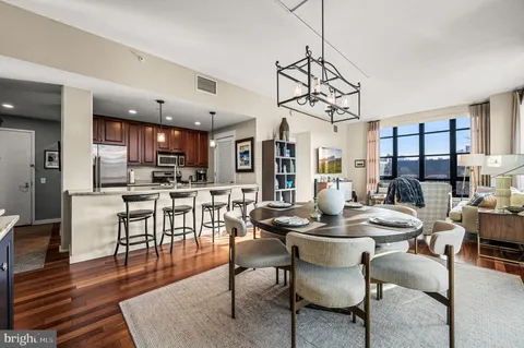 a dining room with wooden floor a chandelier a glass table and chairs