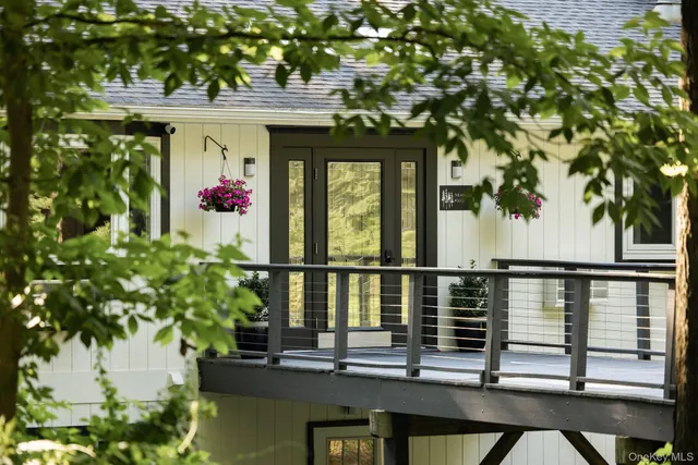 a balcony with table and chairs and potted plants