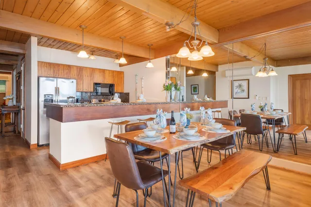 a dining hall with stainless steel appliances kitchen island a table and chairs