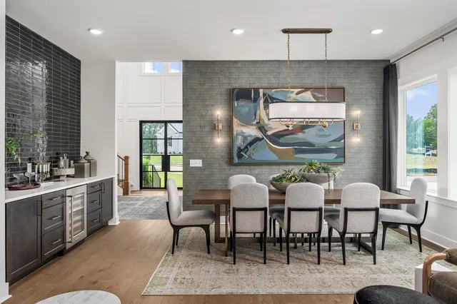 a kitchen with stainless steel appliances kitchen island granite countertop a dining table chairs and a refrigerator