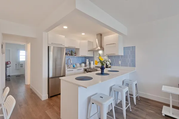 a kitchen with a sink a refrigerator and chairs