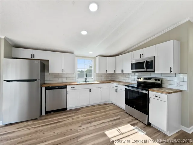 a kitchen with granite countertop a refrigerator stove top oven and sink