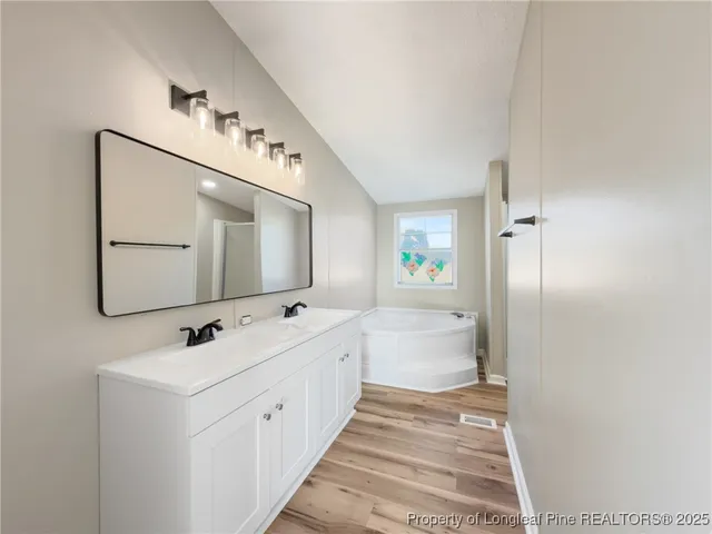 a bathroom with a double vanity sink mirror and bathtub