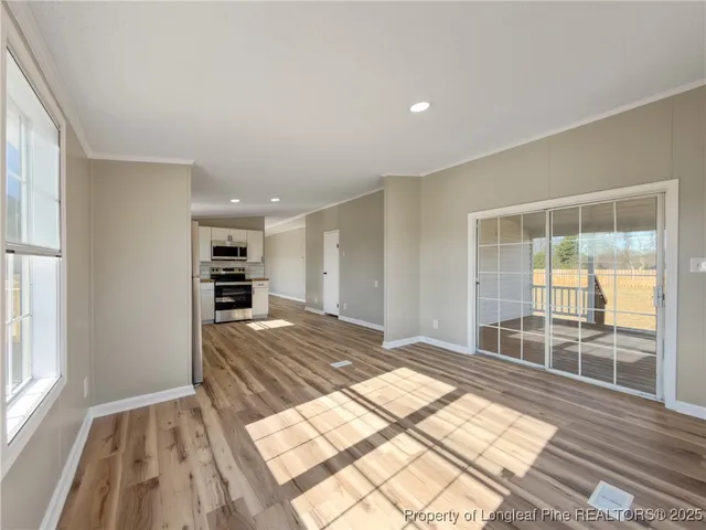 a view of kitchen and empty room with wooden floor and window
