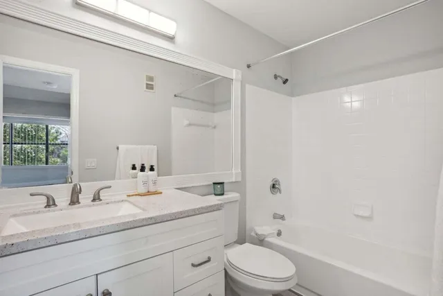 a bathroom with a granite countertop sink a toilet and shower