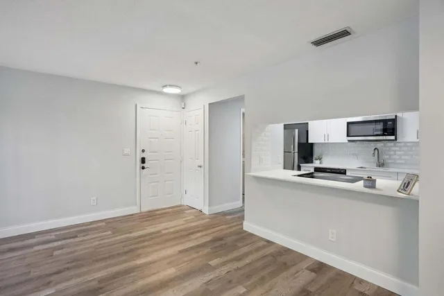 a view of kitchen with stainless steel appliances wooden floor and window
