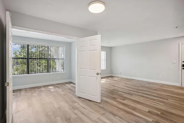 an empty room with wooden floor and windows